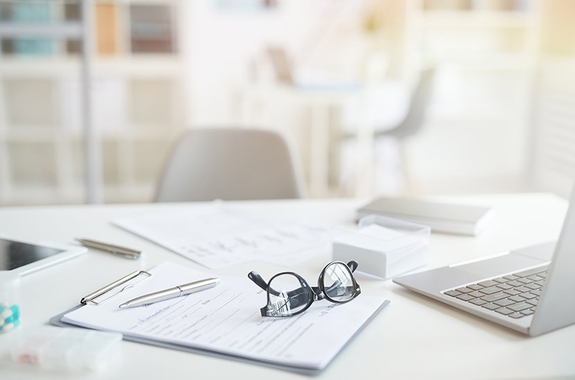 table with laptop, glasses, legal pads and papers